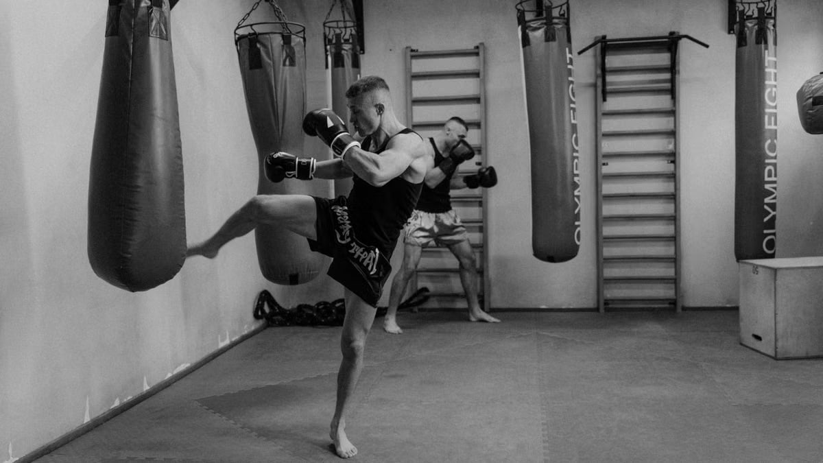 Dynamic action scene of men training with punching bags in a monochrome gym setting.